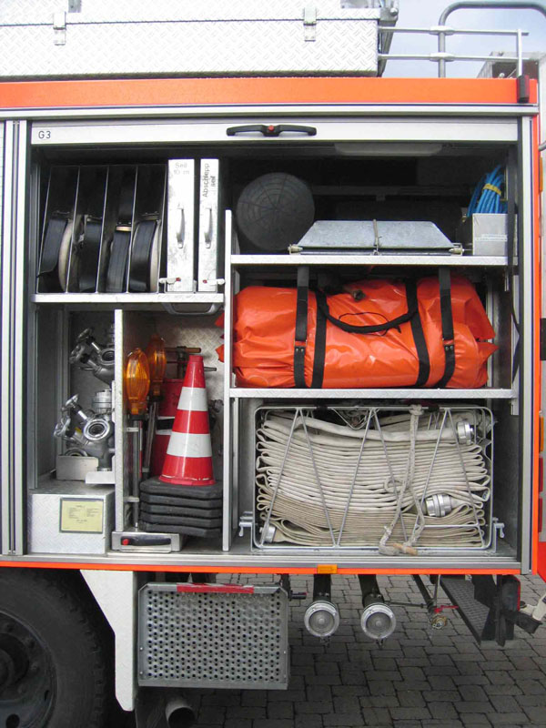 Blick in den Geräteraum G3:

mit C-Schlauchtragekörben, Sprungretter, Kanalblasen, Auffangwannen, weiteren C-Schläuche, Verkehrsabsicherung, Verteilern