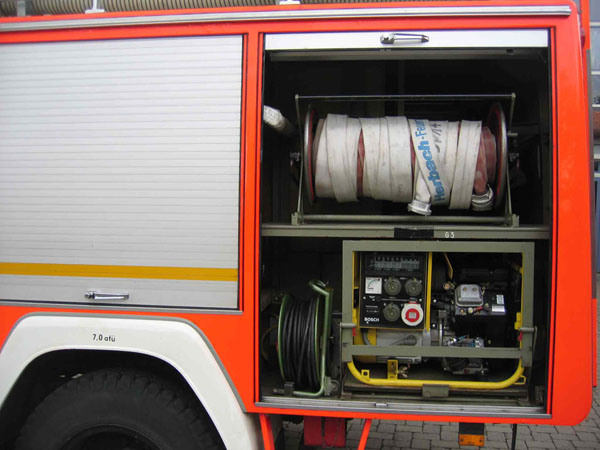 Blick in den Geräteraum G1:

mit C-Schläuchen auf einer Haspel
Stromerzeuger sowie einer Kabeltrommel